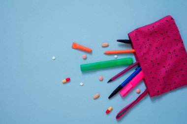 Pembe arka planda renkli kalemlerin ve kırtasiyelerin üst görünümü