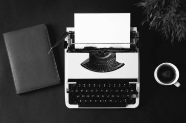 Bilgisayarlı ofis masası, klavye, siyah arka planda kalem ve kahve fincanı.