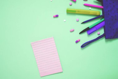 Pembe arkaplandaki kırtasiye ve not defterinin üst görünümü