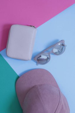 Pembe güneş gözlüğü ve mavi arka planda bir el çantası.