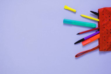 Renkli kalemlerin üst görünümü ve mavi arkaplan üzerine kağıt