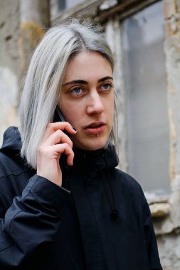 Sokakta akıllı telefon kullanan gümüş saçlı bir kızın portresi.