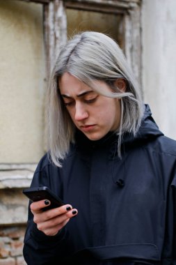 Sokakta akıllı telefon kullanan gümüş saçlı bir kızın portresi.
