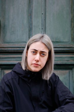 Siyah elbiseli kız eski evin önünde oturuyor.