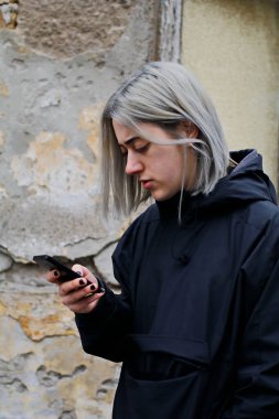 Sokakta akıllı telefon kullanan gümüş saçlı bir kızın portresi.