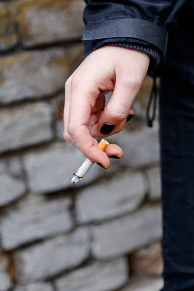 woman hand with black nail polish holding a cigarette