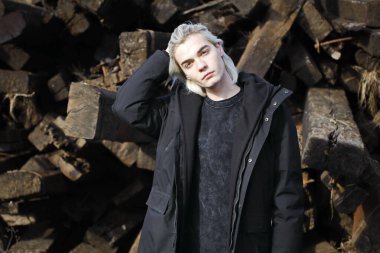 Terk edilmiş tren istasyonunda poz veren siyahlı yakışıklı bir adam.