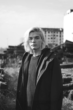 Terk edilmiş tren istasyonunda poz veren siyahlı yakışıklı bir adam.