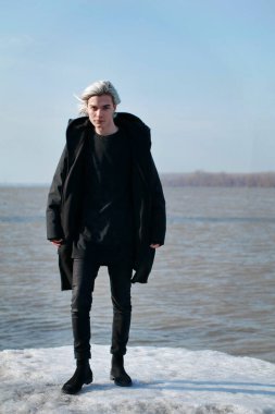 Genç yakışıklı adam nehir kenarında poz veriyor.