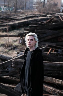 Terk edilmiş tren istasyonunda poz veren siyahlı yakışıklı bir adam.