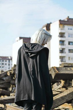 Terk edilmiş tren istasyonunda poz veren siyahlı yakışıklı bir adam.