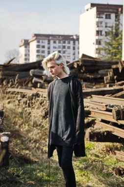 Terk edilmiş tren istasyonunda poz veren siyahlı yakışıklı bir adam.