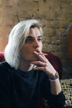 Yakından sigara içen yakışıklı adam.