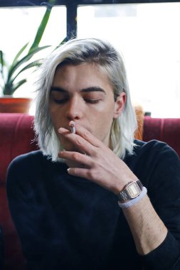 Yakından sigara içen yakışıklı adam.