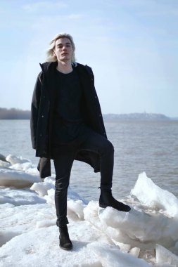 Genç yakışıklı adam nehir kenarında poz veriyor.