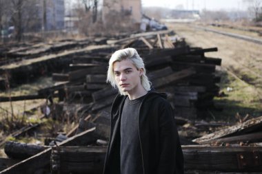 Terk edilmiş tren istasyonunda poz veren siyahlı yakışıklı bir adam.