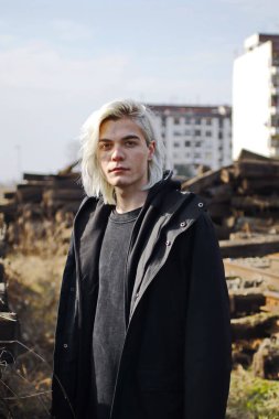 Terk edilmiş tren istasyonunda poz veren siyahlı yakışıklı bir adam.