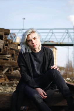 Terk edilmiş tren istasyonunda poz veren siyahlı yakışıklı bir adam.