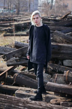 Terk edilmiş tren istasyonunda poz veren siyahlı yakışıklı bir adam.