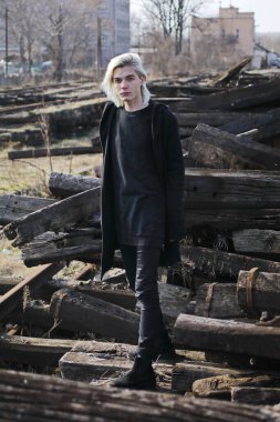 Terk edilmiş tren istasyonunda poz veren siyahlı yakışıklı bir adam.