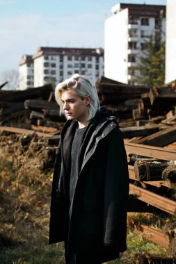 Terk edilmiş tren istasyonunda poz veren siyahlı yakışıklı bir adam.