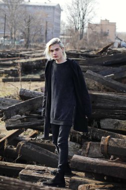 Terk edilmiş tren istasyonunda poz veren siyahlı yakışıklı bir adam.