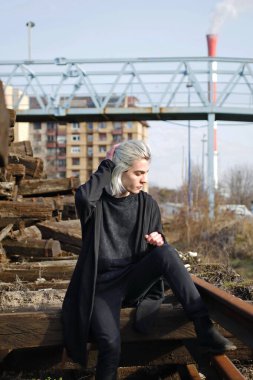 Terk edilmiş tren istasyonunda poz veren siyahlı yakışıklı bir adam.