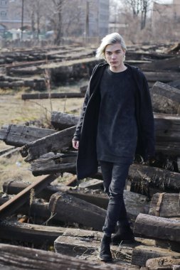 Terk edilmiş tren istasyonunda poz veren siyahlı yakışıklı bir adam.