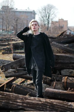 Terk edilmiş tren istasyonunda poz veren siyahlı yakışıklı bir adam.