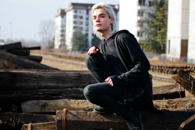 Terk edilmiş tren istasyonunda poz veren siyahlı yakışıklı bir adam.