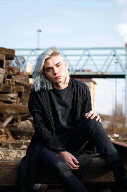 Terk edilmiş tren istasyonunda poz veren siyahlı yakışıklı bir adam.