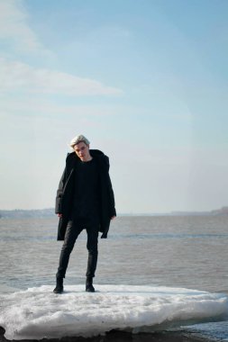 Genç yakışıklı adam nehir kenarında poz veriyor.