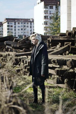 Terk edilmiş tren istasyonunda poz veren siyahlı yakışıklı bir adam.