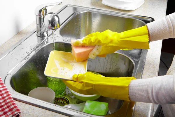 Hands washing dishes with running water from faucet — Stock Photo, Image