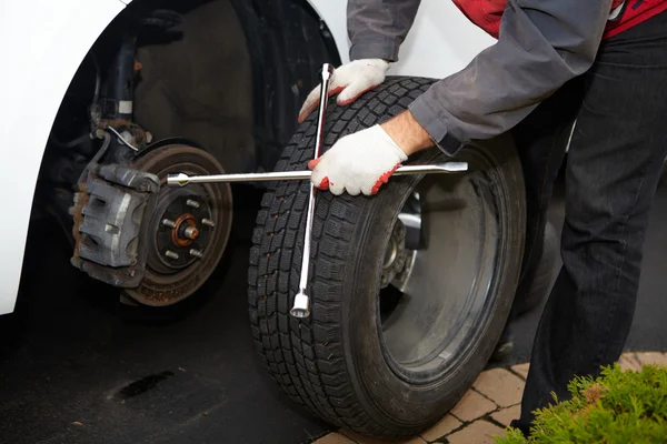 Mecánico de coche cambiando neumático . — Foto de Stock