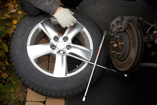 Mecánico de coche cambiando neumático . — Foto de Stock