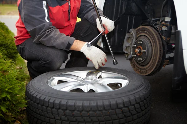 Mecánico de coche cambiando neumático . — Foto de Stock