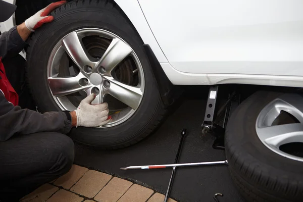 Mecánico de coche cambiando neumático . — Foto de Stock