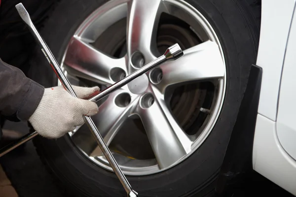 Mecánico de coche cambiando neumático . — Foto de Stock