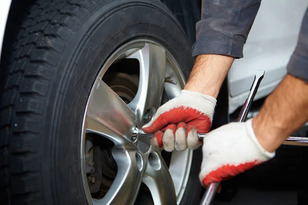 Mecánico de coche cambiando neumático . — Foto de Stock