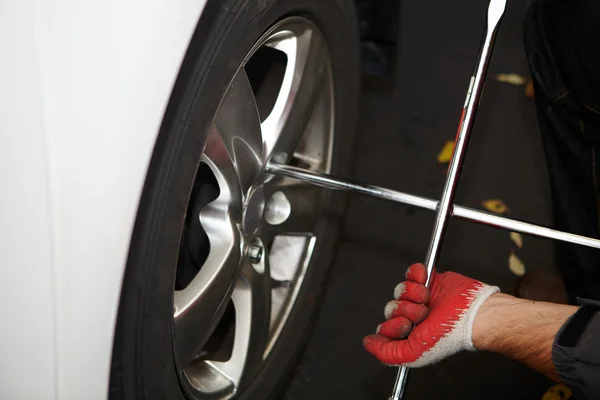 Mecánico de coche cambiando neumático . — Foto de Stock