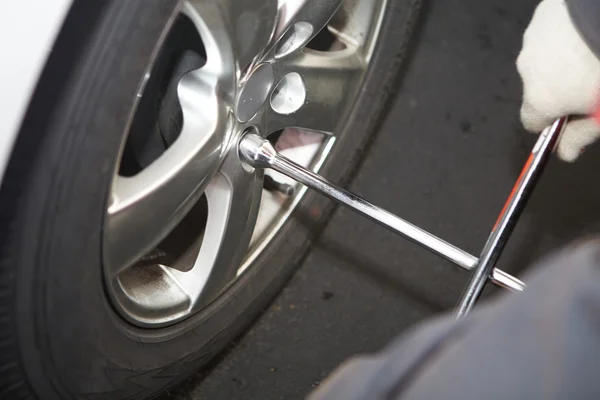 Mecánico de coche cambiando neumático . — Foto de Stock