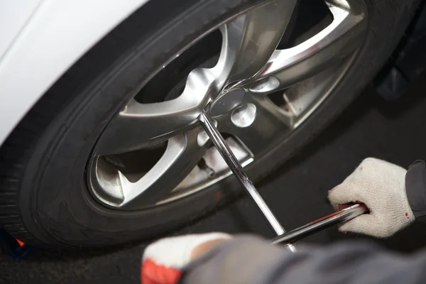 Mecánico de coche cambiando neumático . — Foto de Stock