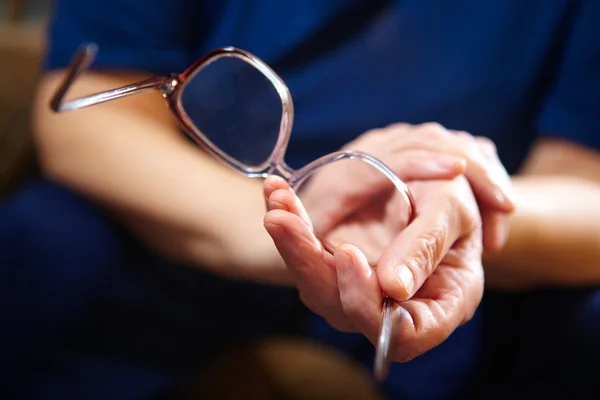 Old woman hands with eyeglasses — Stock Photo, Image