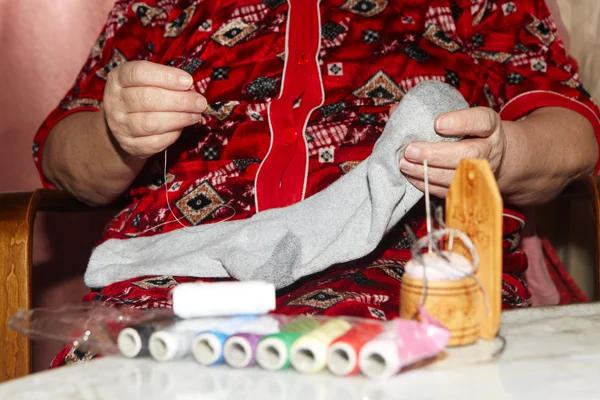 Velha mulher para coser sobre uma lágrima — Fotografia de Stock