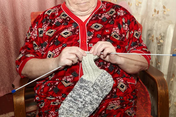 Old woman and knitting clothes — Stock Photo, Image