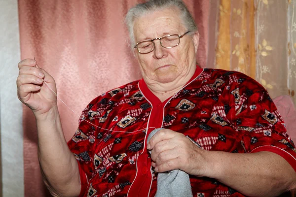 Old woman to sew over a tear — Stock Photo, Image