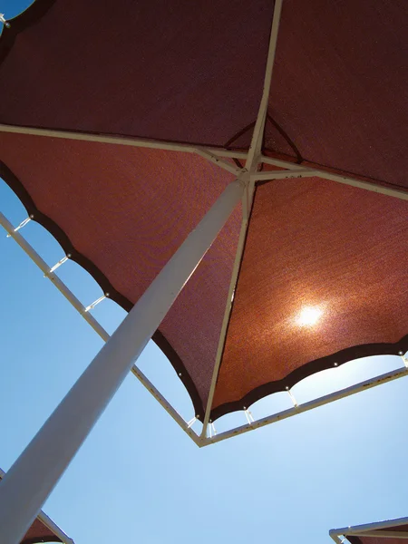 Kırmızı metalik şemsiye plaj şemsiyesi üzerinde mavi gökyüzü — Stok fotoğraf