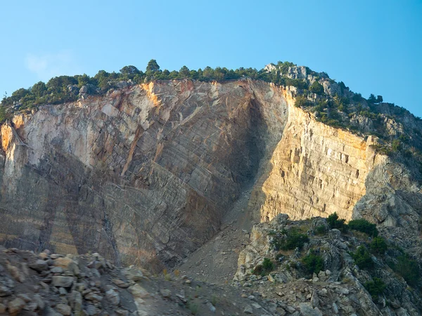 Скалистая скала, горные деревья и голубое небо — стоковое фото