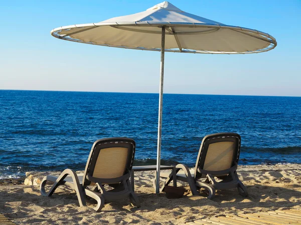 Duas espreguiçadeiras e guarda-chuva na praia de areia azul do mar — Fotografia de Stock